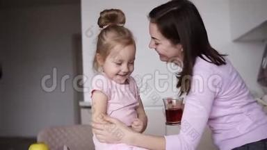 布鲁内特活泼开朗的妈妈正在和她的小女儿玩，一边亲吻，一边拥抱，一边挠她的痒痒
